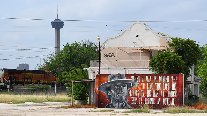 A new mural by @soupLAWS in back of a building shaped like the Alamo at Essex Modern City with a train and the Tower of the Americas in the background. That's a very San Antonio kind of scene.