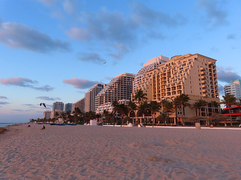 High rises that are home to luxury hotels and condos face the beach and have an orange glow as the sun rises over the Atlantic Ocean at Fort Lauderdale Beach. - photo by Joe Alexander